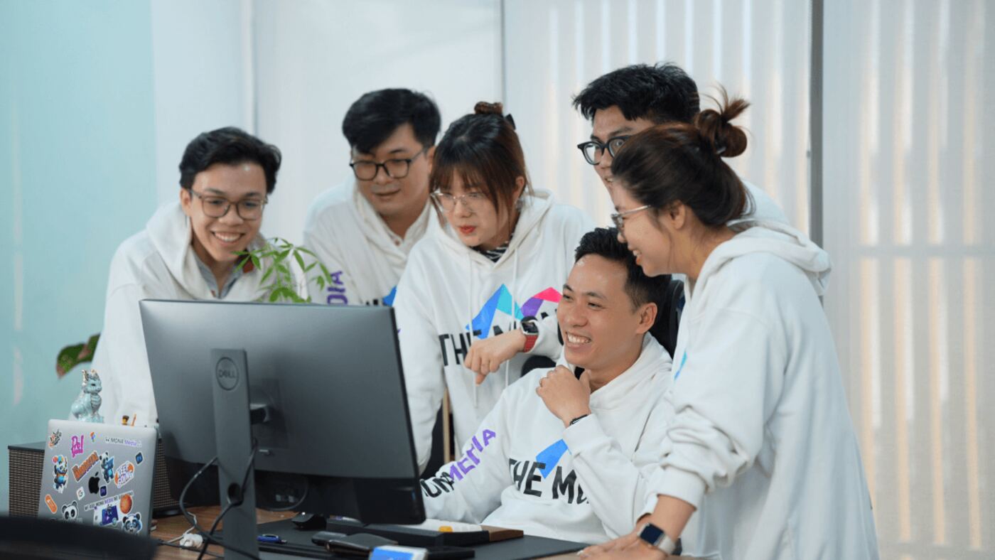 Đội ngũ MONA mặc hoodie THE MONA cùng xem màn hình tại văn phòng
